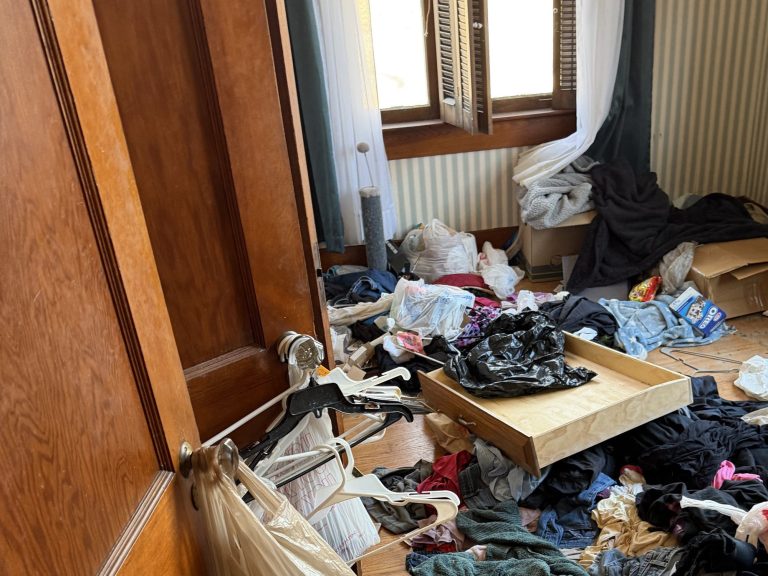 Furniture, bags, and household contents filling a hardwood-floor room before an eviction cleanout